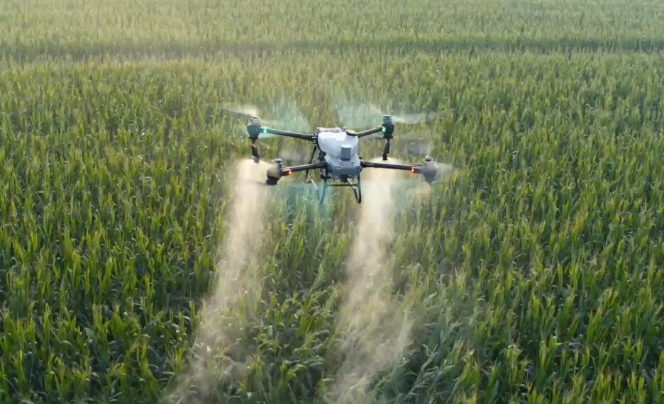 Drone agrícola DJI AGRAS T50 pulverizando uma lavoura verde